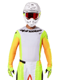 Alpinestars 2025 Techstar Melt Jersey, motocross racing gear, white chest with neon yellow and orange sleeves, rider wearing white helmet and red goggles, neon yellow gloves with black logos, vibrant colorway for off-road performance