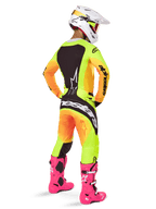 Motocross rider from the back wearing Alpinestars 2025 Techstar Melt Jersey, vibrant yellow and orange gradient with black sections, matching motocross pants, bright pink boots, and white helmet, athletic fit for off-road competition.