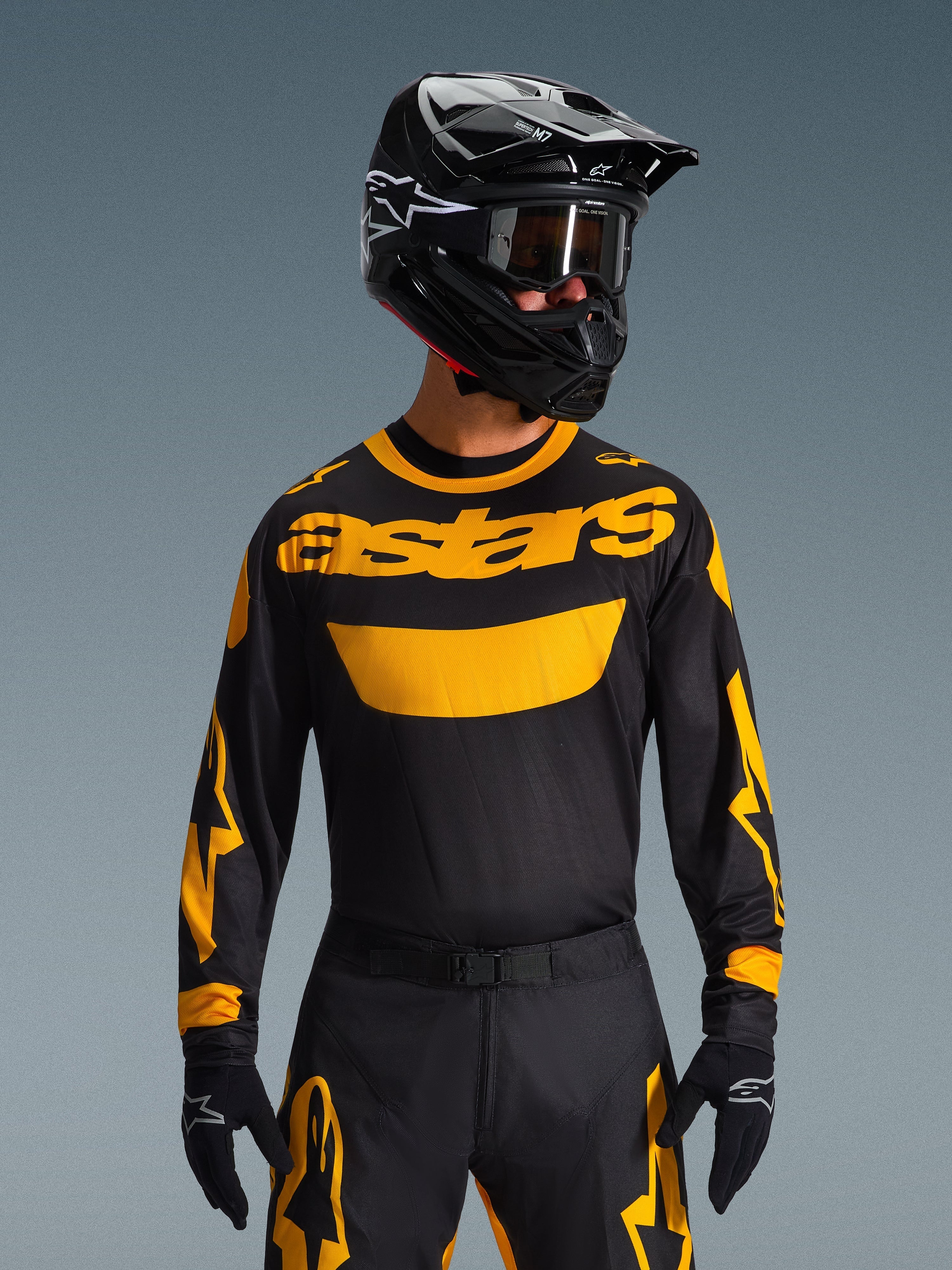 Motocross-Fahrer trägt das Alpinestars 2026 Racer Riway Trikot in Gelb und Schwarz, mit einem auffälligen gelben „astars“-Logo auf der Brust, kombiniert mit einer passenden schwarz-gelben Hose, einem schwarzen Helm mit Brille und schwarzen Handschuhen, professionelles Offroad-Rennbekleidungsset.