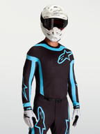 Alpinestars Supertech Vesta Trikot, Motocross-Trikot für Herren, Schwarz und Türkis, lasergefertigte Belüftungsöffnungen und athletische Rennpassform, am Modell getragen.
