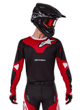 Alpinestars 2025 Racer Veil Jersey, Motocross-Trikot, Schwarz und leuchtendes Rot, kombiniert mit passender Hose, schwarzem Helm und roter Brille, markante weiße Logos und schnittiges Renn-Design, Performance-Ausrüstung für Offroad-Motocross