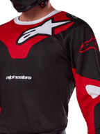 Alpinestars 2025 Racer Veil Trikot, Motocross-Trikot, Schwarz und leuchtendes Rot, Nahaufnahme mit großem weißen Astars-Logo auf rotem Brustpanel, weißer Markenschriftzug und technisches feuchtigkeitsableitendes Material.