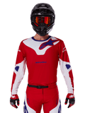 Alpinestars 2025 Racer Veil Trikot, Motocross-Trikot, Rot, Weiß und Blau, Langarm, getragen mit schwarzem Helm und orangefarbener Brille, dazu passende rote Handschuhe und Hosen, schlankes Performance-Design für Offroad-Fahrten