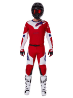 Motocross-Fahrer im Alpinestars 2025 Racer Veil Ausrüstungsset, Trikot und Hose in leuchtendem Rot und Weiß mit blauen Akzenten, schwarzer Helm mit roter Brille, weiße Stiefel und rot-schwarze Handschuhe, koordiniertes Outfit für Offroad-Rennen