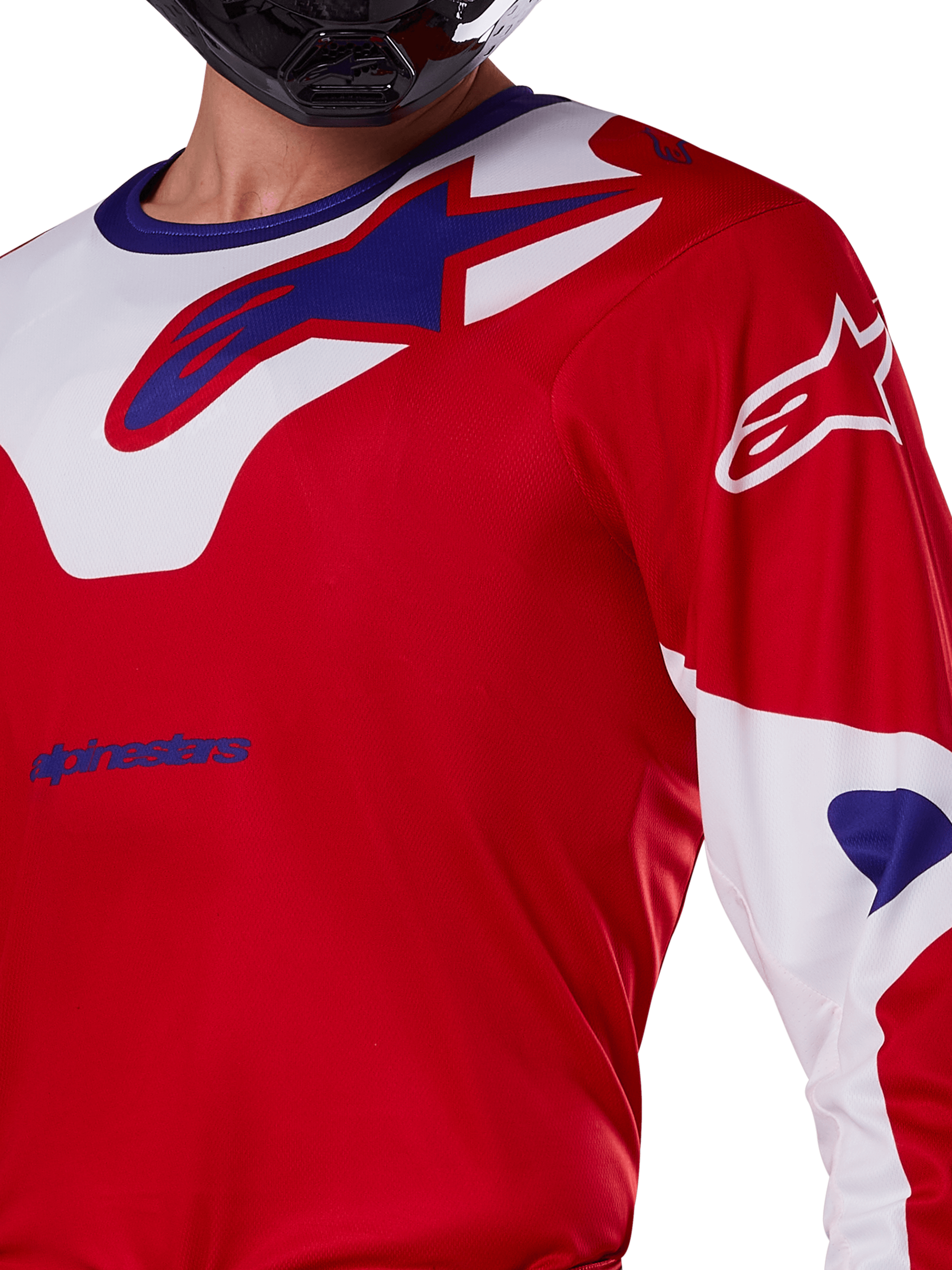 Alpinestars 2025 Racer Veil Trikot, Motocross-Trikot, Hellrot und Weiß, Nahaufnahme des Oberkörpers und Brustbereichs, blaues Alpinestars-Logo auf weißem Krageneinsatz, rote Ärmel mit weißen Akzenten, getragen mit einem schwarzen Helm, technische Offroad-Fahrbekleidung