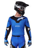 Alpinestars 2025 Racer Veil Jersey, Motocross-Trikot, Blau und Schwarz, getragen mit passender Motocross-Ausrüstung einschließlich Helm und Handschuhen, sportliches Design mit weißem Alpinestars-Branding