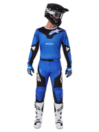 Motocross-Fahrer im Alpinestars 2025 Racer Veil Gear Set, blau-schwarzes Trikot mit passender Hose, schwarzer Helm mit weißer Brille, weiß-schwarze Stiefel, abgestimmtes Rennoutfit für Offroad-Motocross.