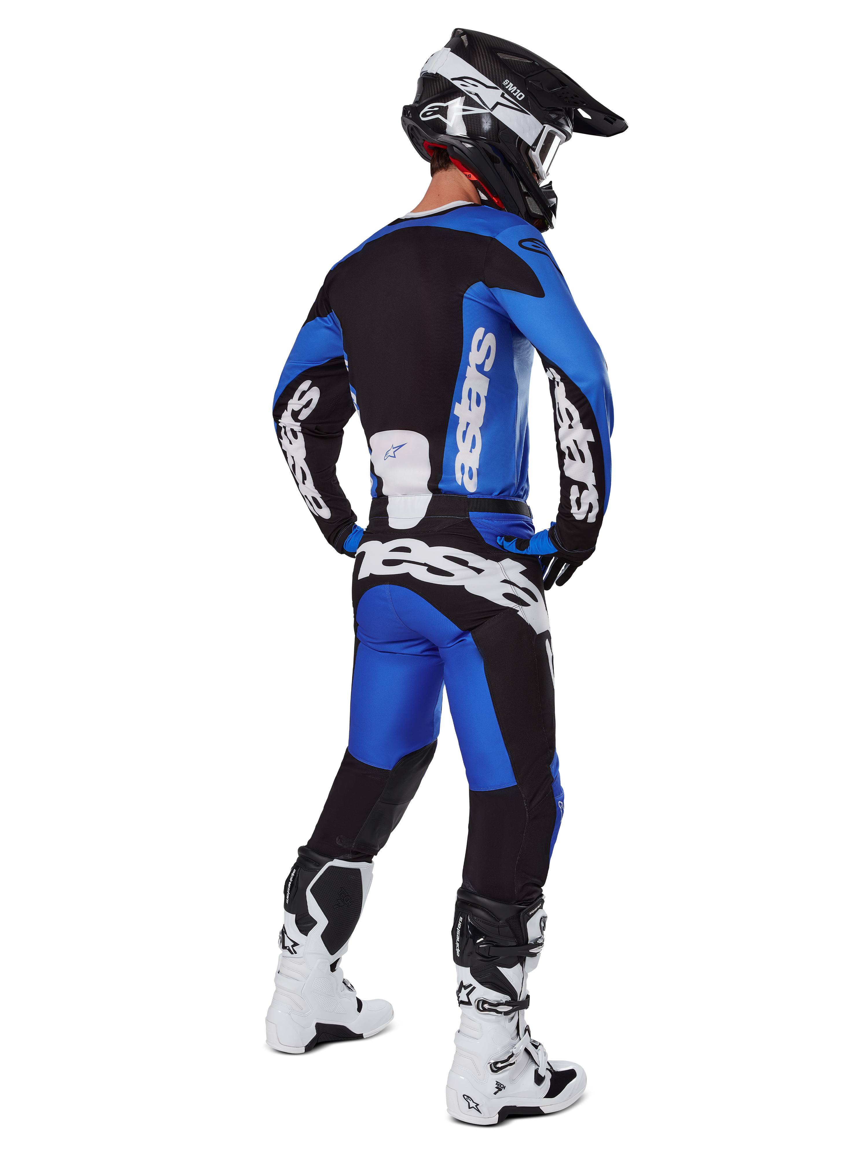 Motocross-Fahrer in kompletter Rennausrüstung von hinten gesehen, 2025 Racer Veil Trikot und passende Hose in Blau und Schwarz, mit weißem Alpinestars-Branding, schwarzem Helm, weiß-schwarzen Stiefeln, koordiniertes Outfit für den Offroad-Rennsport