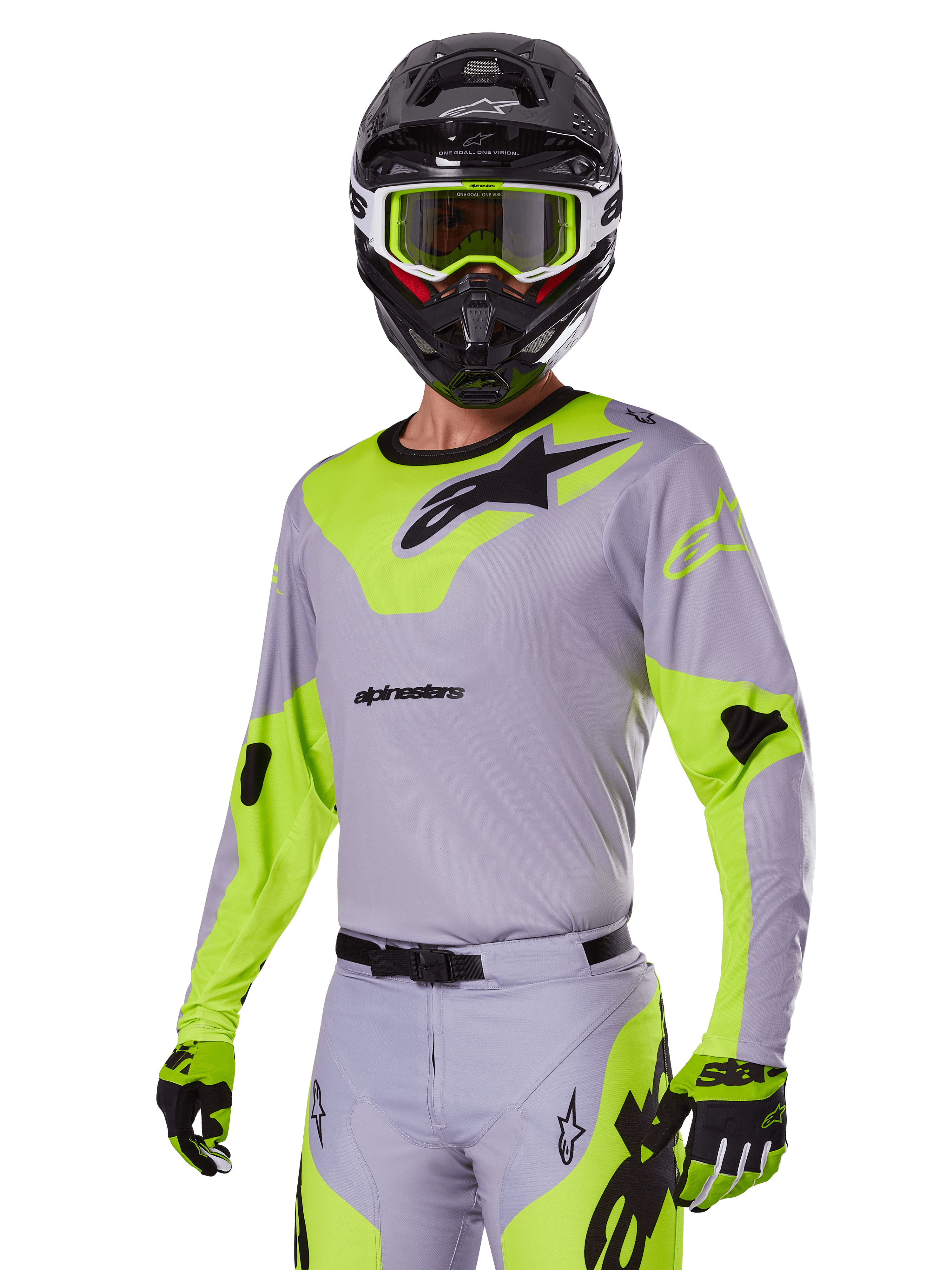 Motocross rider wearing Alpinestars 2025 Racer Veil Gear Set in Gray and fluo green, light gray jersey and pants with bold neon yellow-green panels and black Alpinestars logos, coordinated with matching gloves and a black helmet with neon green goggles, professional off-road racing apparel.