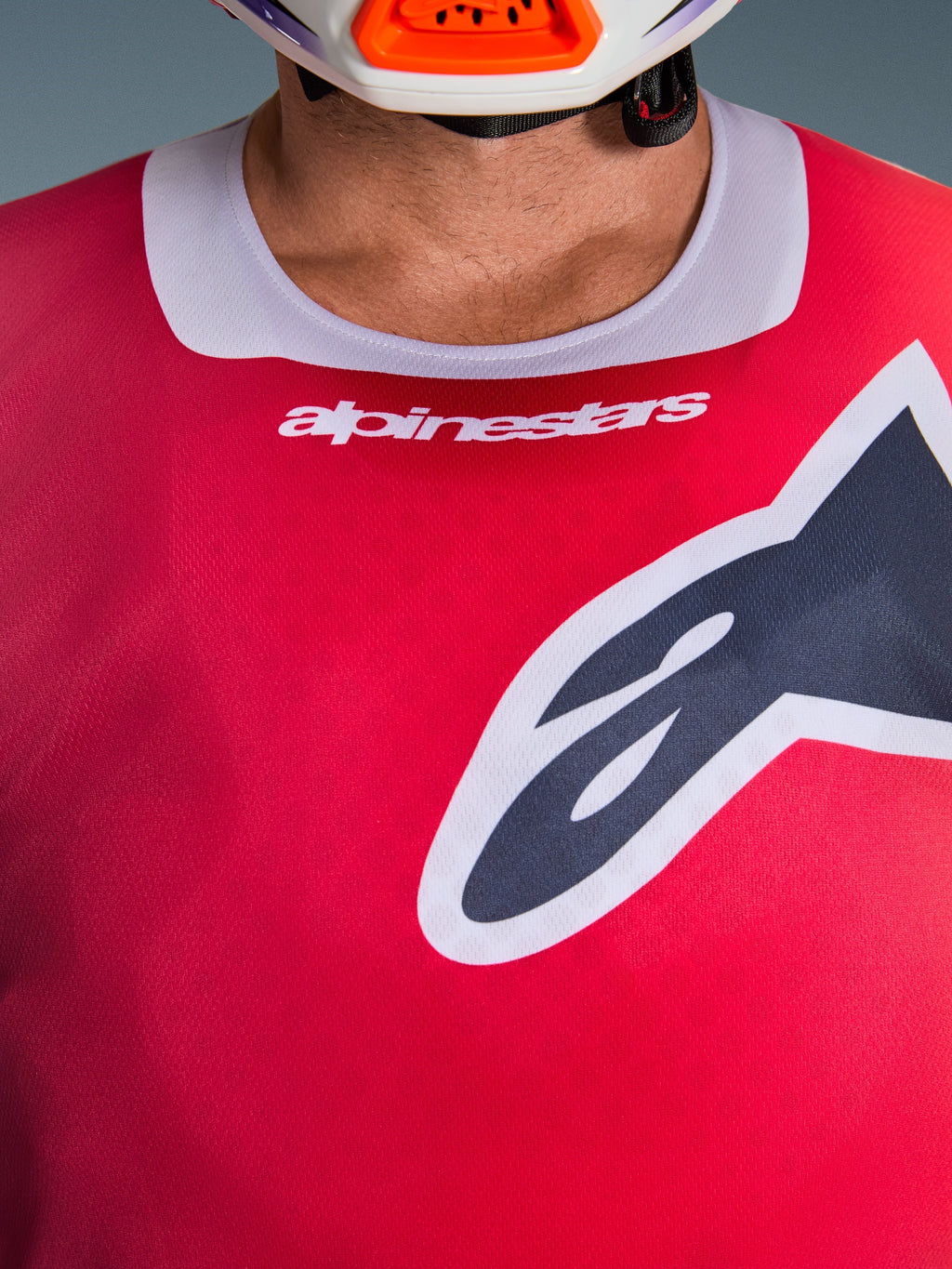 Nahaufnahme des Alpinestars 2026 Racer Portl Trikots in Rot, mit hellgrauem Stretch-Kragen, weißem Branding und einem großen schwarzen Astars-Logo auf der Brust, Performance-Motocross-Rennausrüstung