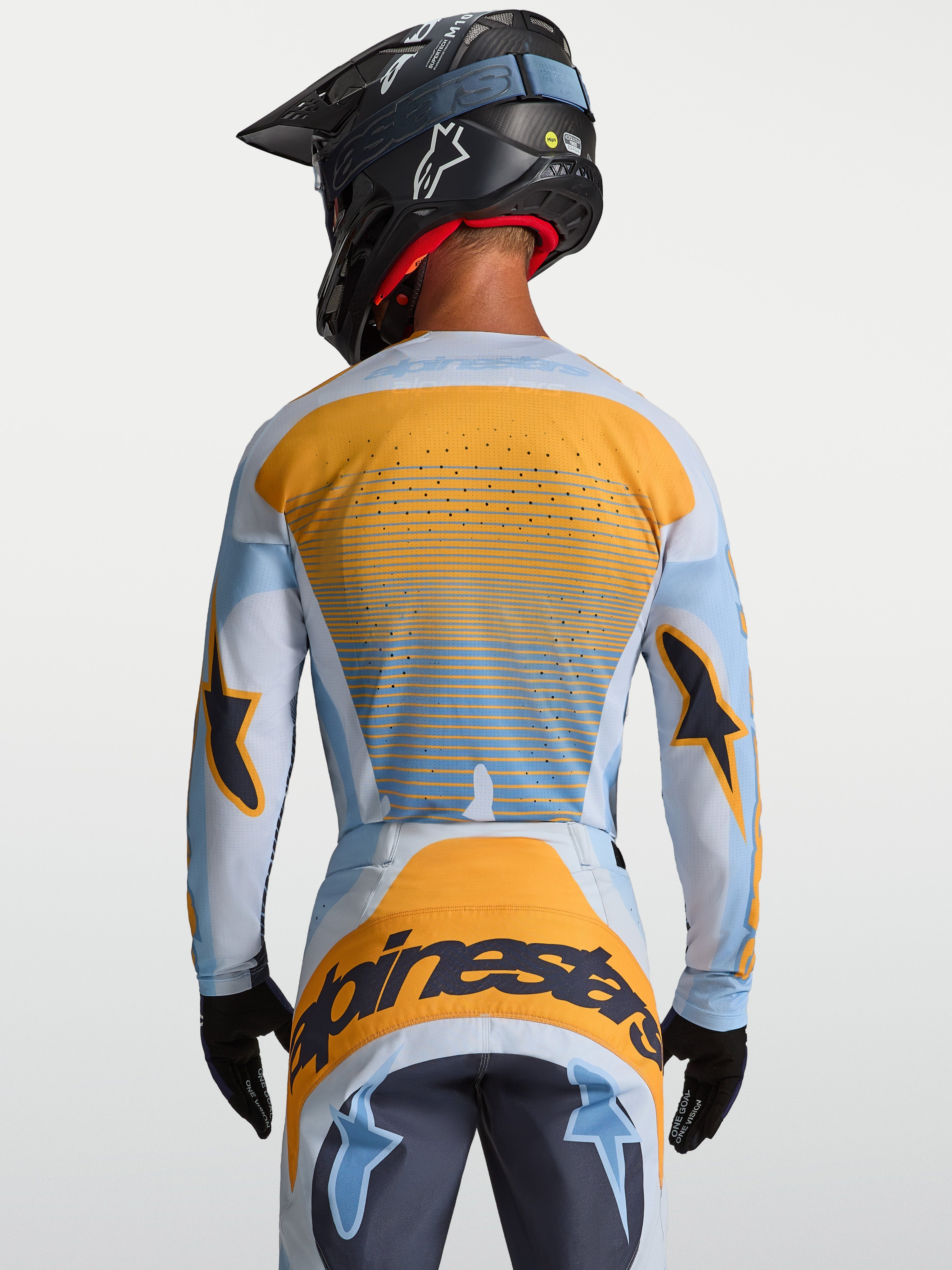 Alpinestars Techstar Maven Trikot, Motocross-Trikot für Herren, Blau und Orange, Rückansicht mit lasergeschnittener Belüftung, getragen von einem Fahrer mit Helm, ideal für MX und Enduro