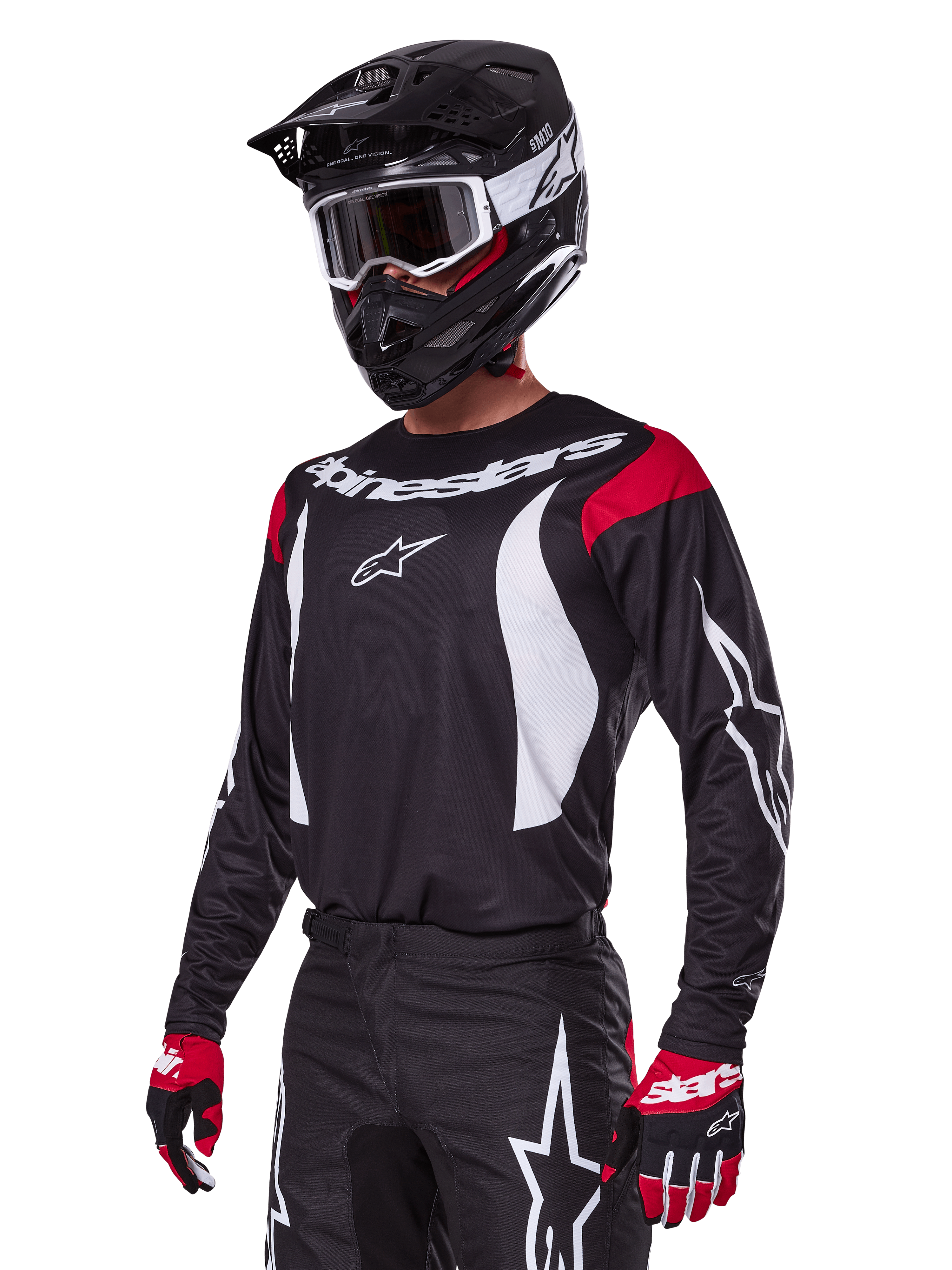Motocross-Fahrer im Alpinestars 2025 Fluid Haul Ausrüstungsset, schwarzes Trikot mit roten Schultereinsätzen und weißen Grafiken, passende schwarze Hose mit weißen Stern-Logos, rote und schwarze Handschuhe, schwarzer Helm mit weißen Akzenten und Schutzbrille, abgestimmte Motocross-Bekleidung.