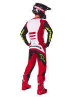 Motocross rider from behind wearing the Alpinestars 2025 Fluid Haul Gear Set, Bright Red and Black with white panels, neon yellow branding on sleeves and pants, matching red boots and black helmet, complete professional off-road racing gear.