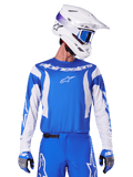 Alpinestars 2025 Fluid Haul Trikot, Motocross-Trikot, Blau und Weiß, getragen mit passender Hose und Handschuhen, weißer Helm mit blauer Brille, koordiniertes MX-Ausrüstungsset für Geländefahrten