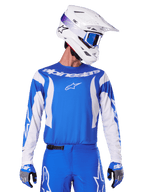 Alpinestars 2025 Fluid Haul Trikot, Motocross-Trikot, Blau und Weiß, getragen mit passender Hose und Handschuhen, weißer Helm mit blauer Brille, koordiniertes MX-Ausrüstungsset für Geländefahrten