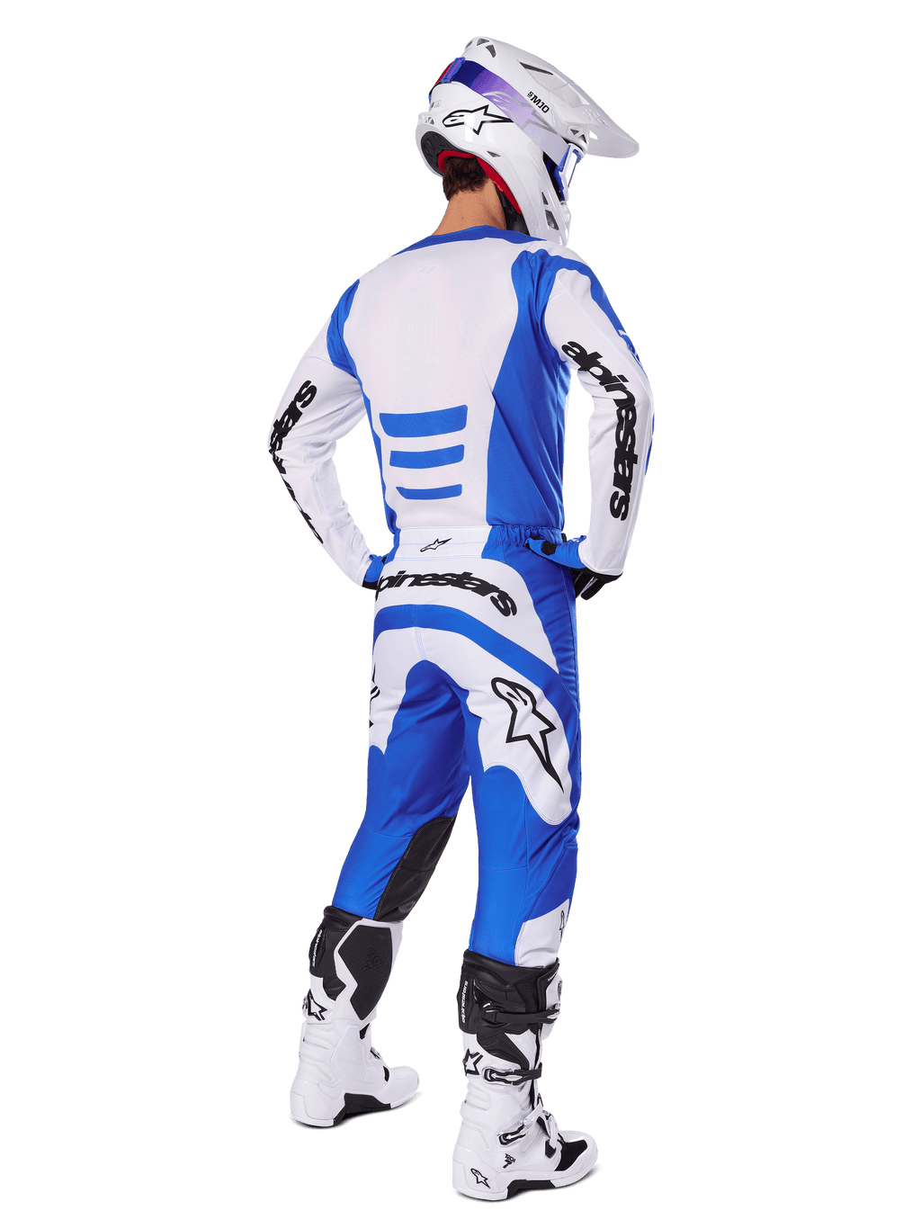 Motocross-Fahrer von hinten im Alpinestars 2025 Fluid Haul Gear Set, blau-weißes Trikot mit passender Hose, weißer Helm mit blauen Akzenten und weiß-schwarze Rennstiefel, koordiniertes Offroad-Rennoutfit
