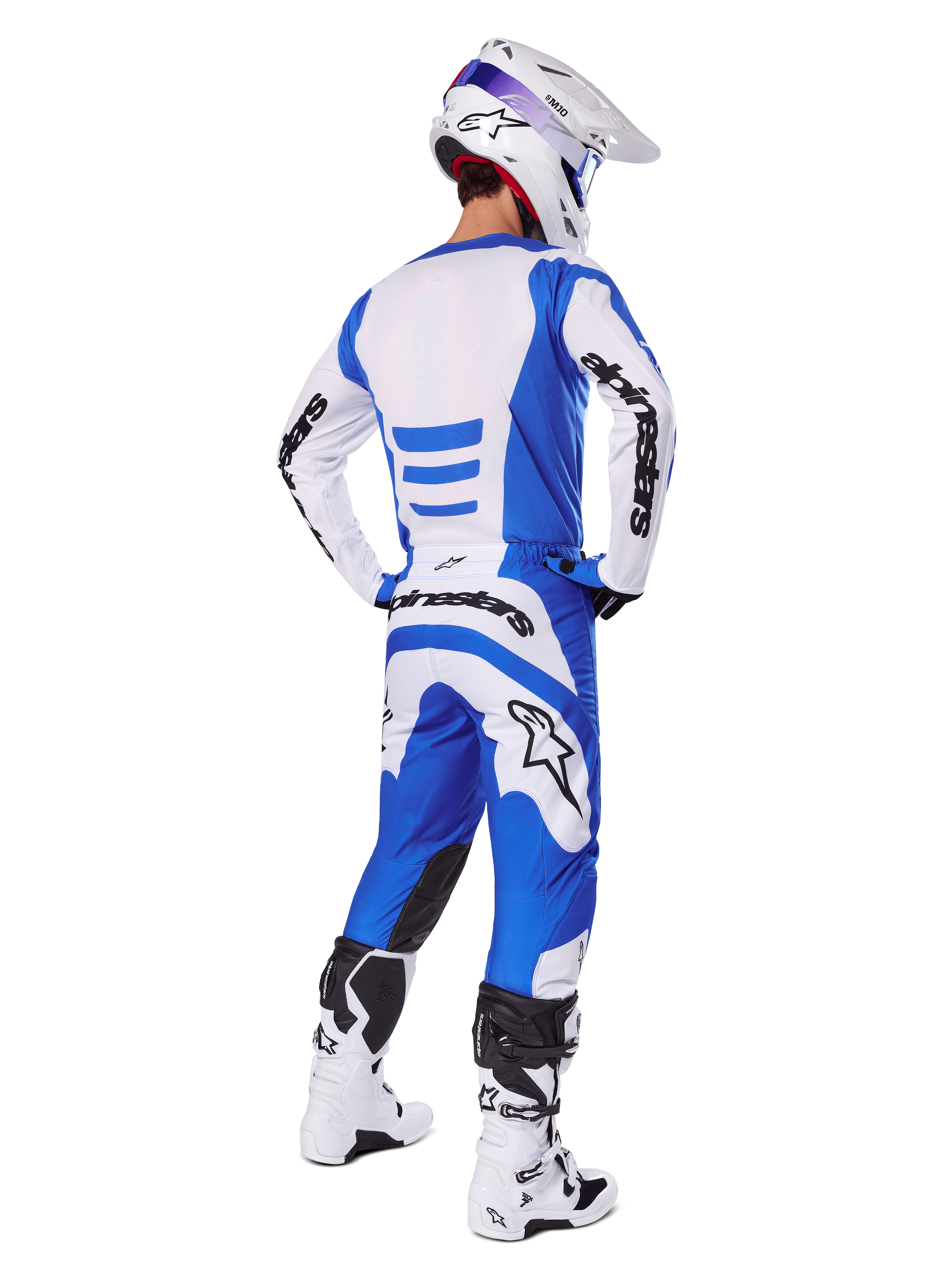 Motocross-Fahrer von hinten im Alpinestars 2025 Fluid Haul Gear Set, blau-weißes Trikot mit passender Hose, weißer Helm mit blauen Akzenten und weiß-schwarze Rennstiefel, koordiniertes Offroad-Rennoutfit