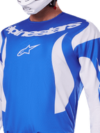Alpinestars 2025 Fluid Haul Trikot, Blau und Weiß, getragen von einem Fahrer mit weißem Helm, mit weißem Alpinestars-Schriftzug und A-Star-Logo, sportliche Passform, leichtes feuchtigkeitsableitendes Material für Motocross und Offroad-Fahrten