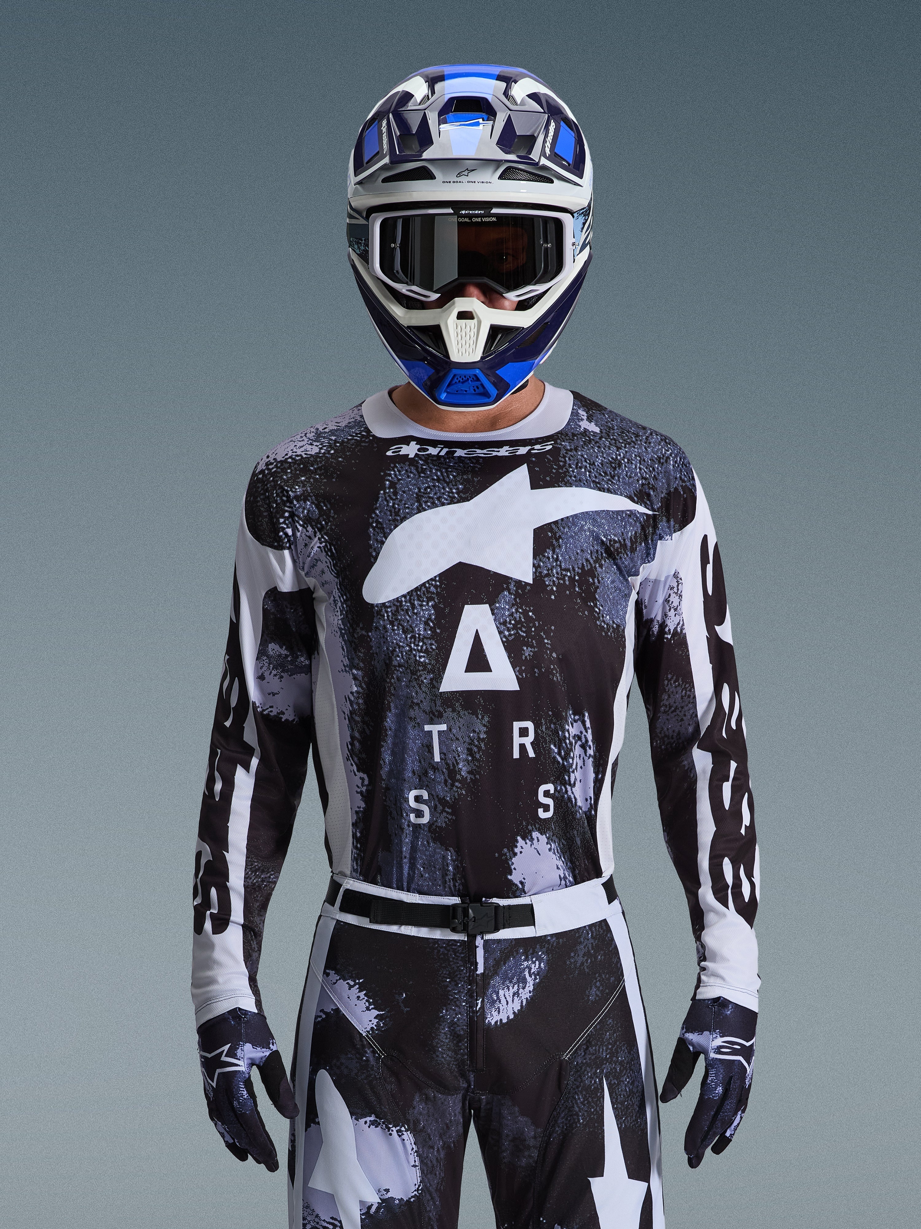 Alpinestars 2026 Racer Lahnd Trikot, Motocross-Ausrüstung, Iron Camo-Muster in Schwarz und Weiß, mit markantem Stern-Logo und ASTARS-Schriftzug, getragen mit passender Hose und einem blauen Motocross-Helm