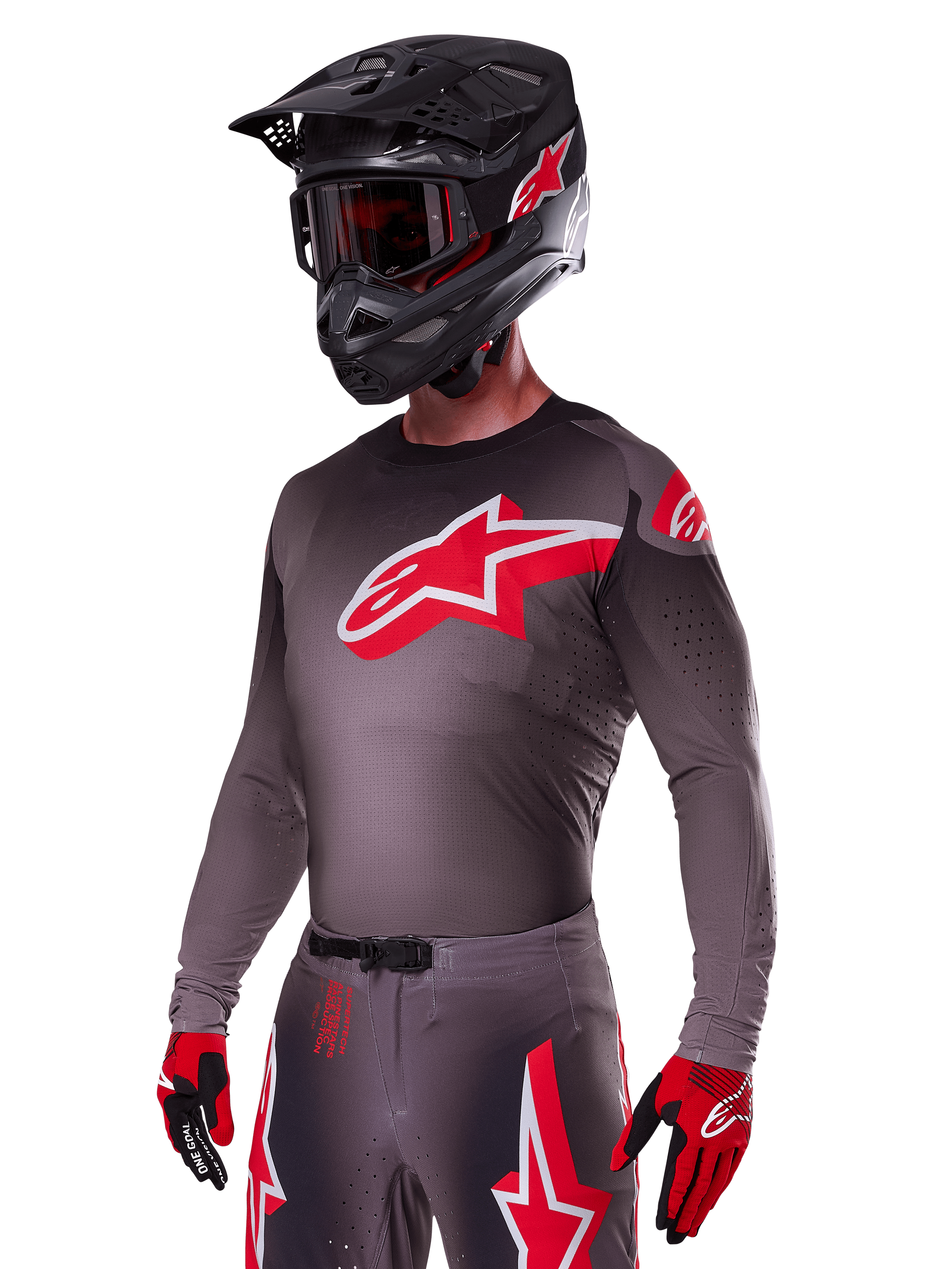 Alpinestars 2025 Supertech Lipan Gear Set, Motocross rider wearing a dark grey jersey and pants with red and white accents, featuring a large red Alpinestars logo on the chest, laser-cut perforations for ventilation, matching black helmet, red goggles, and red and black gloves.