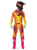 Motocross-Fahrer in kompletter Rennausrüstung, 2025 Supertech Lipan Trikot und Hose mit gelb-orangefarbenem Farbverlauf und pinken Akzenten, schwarzer Helm mit passenden pinken Grafiken, leuchtend pinke Stiefel und neongrüne Handschuhe, abgestimmtes Alpinestars Offroad-Rennoutfit.