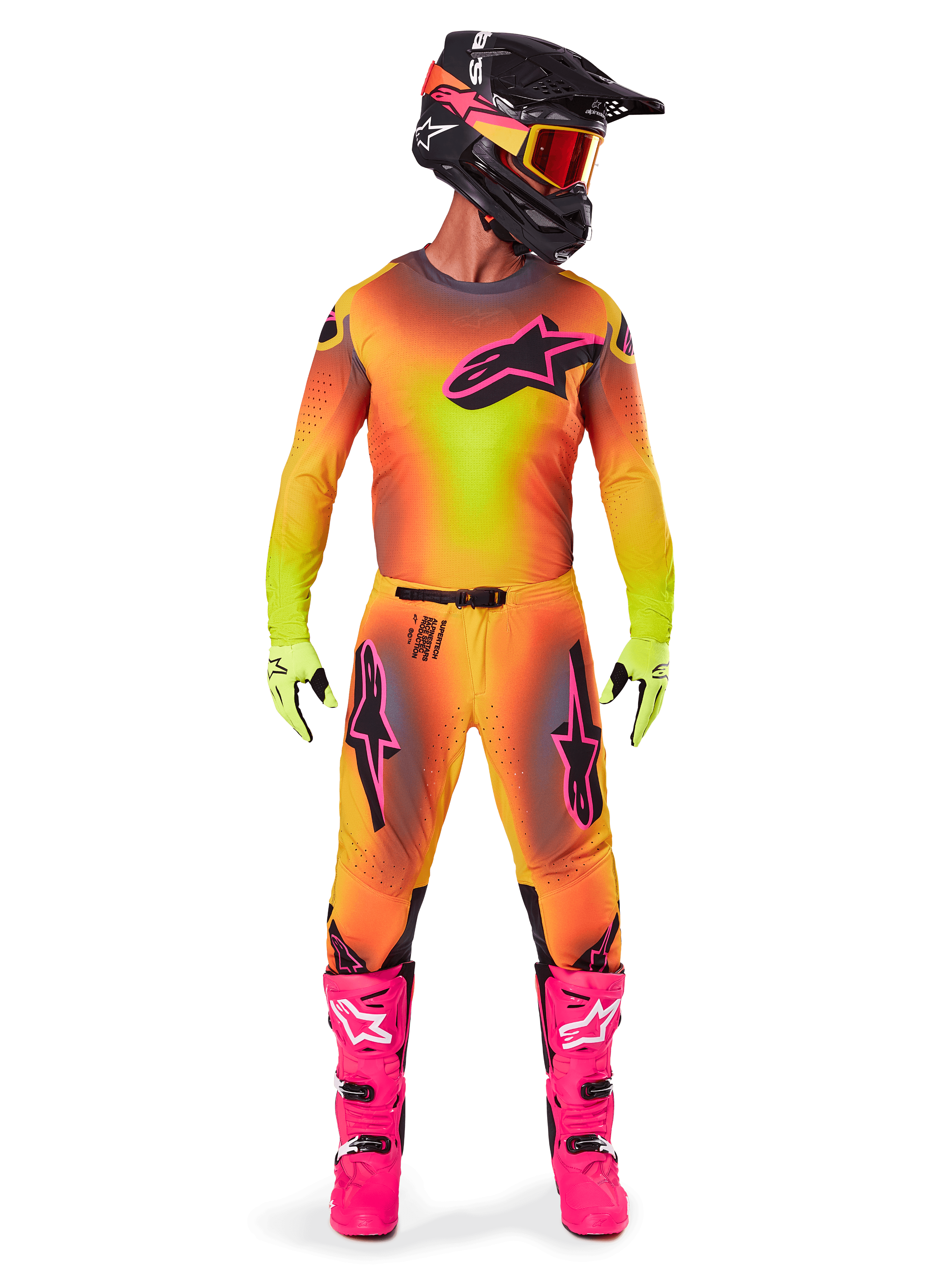 Motocross-Fahrer in kompletter Rennausrüstung, 2025 Supertech Lipan Trikot und Hose mit gelb-orangefarbenem Farbverlauf und pinken Akzenten, schwarzer Helm mit passenden pinken Grafiken, leuchtend pinke Stiefel und neongrüne Handschuhe, abgestimmtes Alpinestars Offroad-Rennoutfit.