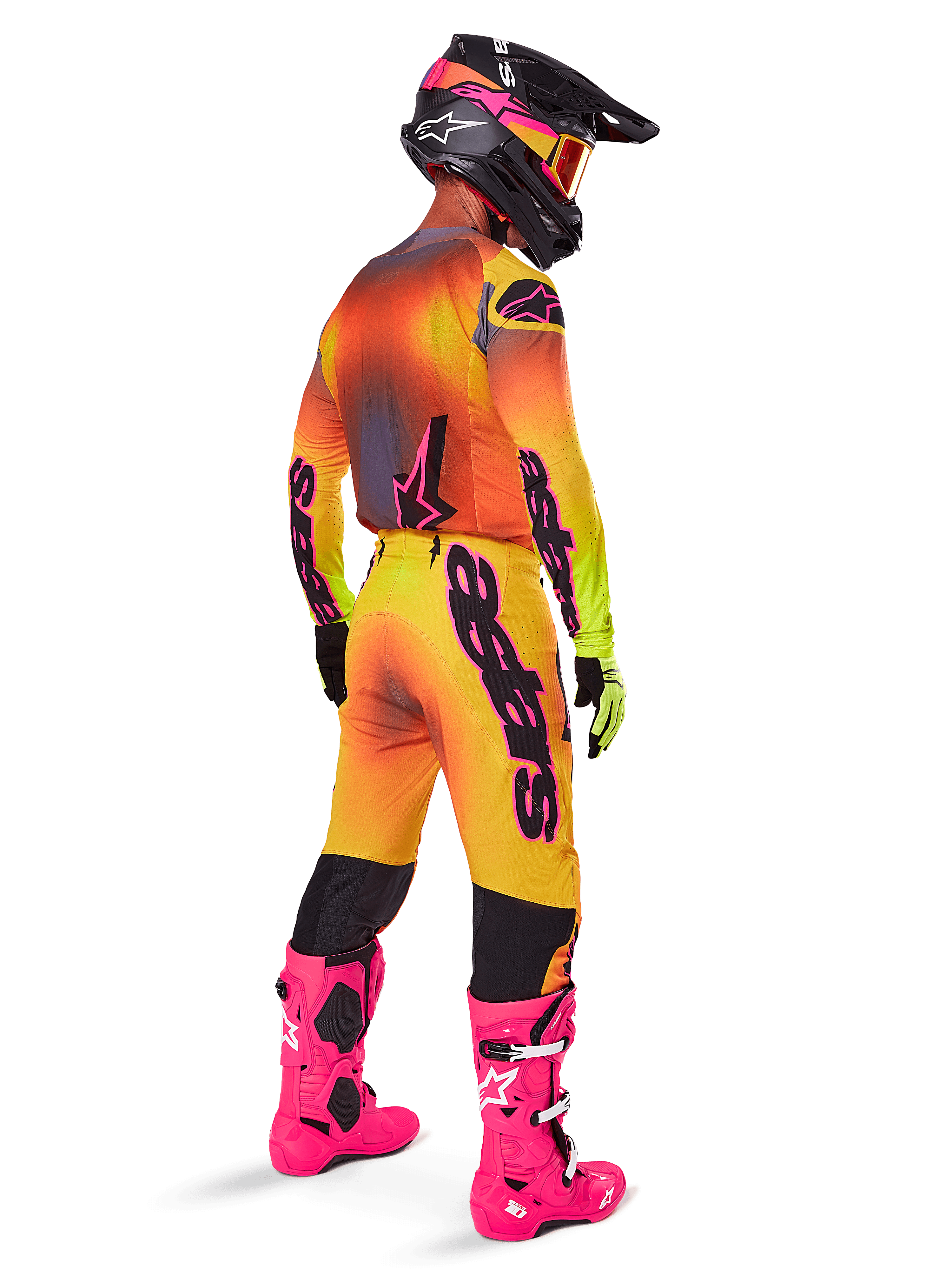 Motocross-Fahrer von hinten im Alpinestars 2025 Supertech Lipan Ausrüstungsset, gelb-orangefarbenes Trikot mit Farbverlauf und pinken Akzenten, passende Hose, leuchtend pinke Stiefel und schwarzer Helm mit pink-gelben Grafiken, koordiniertes Outfit für professionellen Rennsport