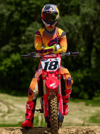 Motocross-Fahrer auf einem roten Honda Dirtbike mit Startnummer 18, Alpinestars 2025 Supertech Lipan Trikot und passende Hose in Gelb und Pink, leuchtend pinke Alpinestars Stiefel, Red Bull Helm, professionelle Rennausrüstung für Offroad-Performance