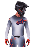2025 Supertech Lipan Jersey, Motocross Racing Jersey, Gray with Orange and Navy Blue accents, long-sleeve performance top with perforated ventilation details, worn with black helmet and red gloves, sleek racing design