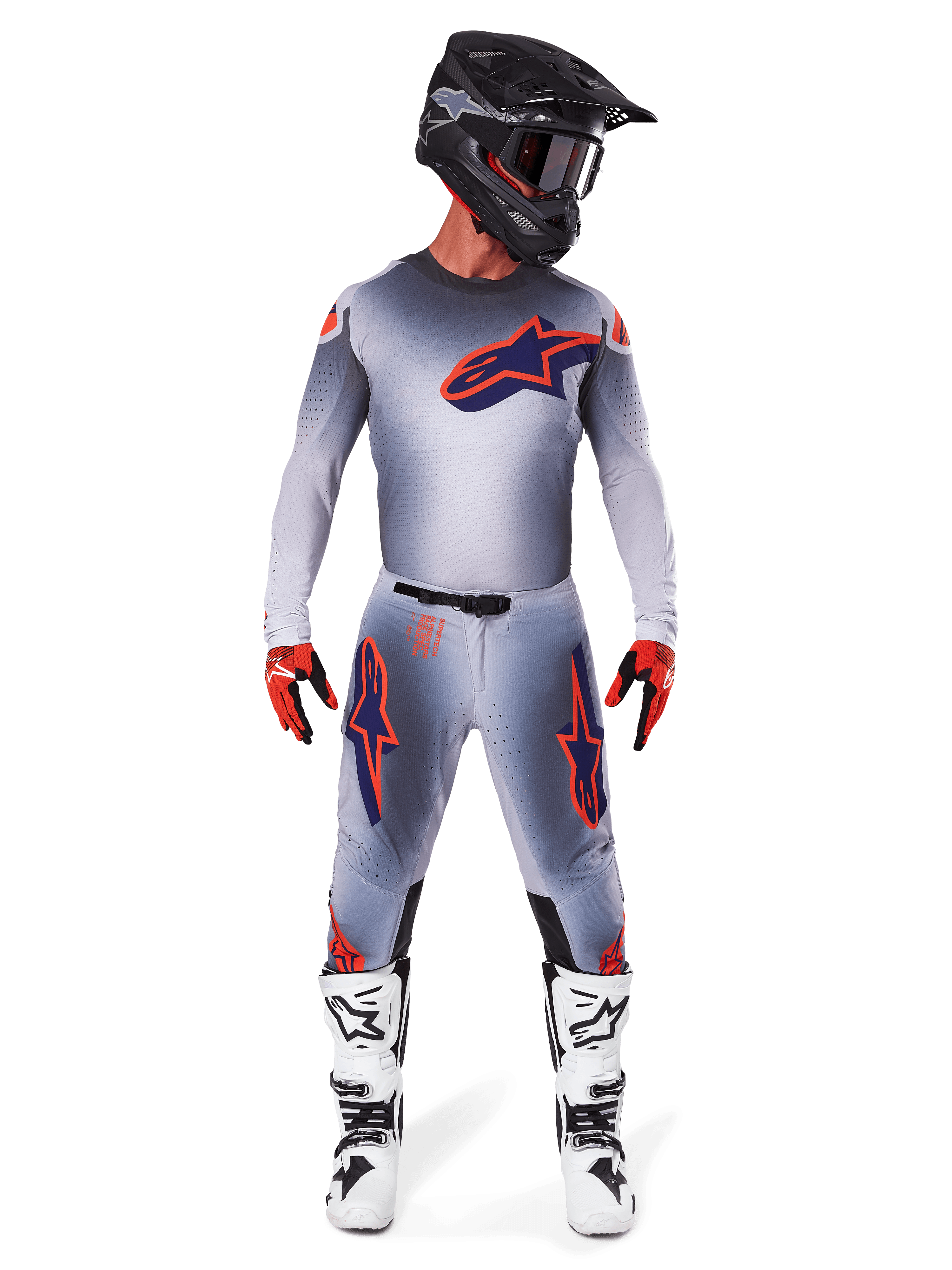 Motocross-Fahrer im 2025 Supertech Lipan Ausrüstungsset in Grau Orange Fluo, graues Trikot mit orangefarbenen Akzenten und navyblauem Alpinestars-Logo, passende graue Hose mit großen Logos an den Oberschenkeln, mattschwarzer Helm, weiß-schwarze Stiefel und rot-schwarze Handschuhe, komplette Profi-Rennausrüstung.