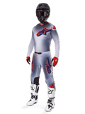 Alpinestars 2025 Supertech Lipan Gear Set, Motocross-Rennausrüstung, Grau mit neonorangen und navyblauen Sterngrafiken, getragen mit schwarzem Helm, rot-schwarzen Handschuhen und weiß-schwarzen Stiefeln, komplette professionelle Offroad-Ausrüstung mit belüftetem Design