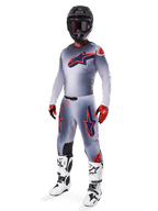 Alpinestars 2025 Supertech Lipan Gear Set, Motocross-Rennausrüstung, Grau mit neonorangen und navyblauen Sterngrafiken, getragen mit schwarzem Helm, rot-schwarzen Handschuhen und weiß-schwarzen Stiefeln, komplette professionelle Offroad-Ausrüstung mit belüftetem Design