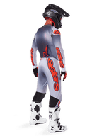 Motocross-Fahrer von hinten im 2025 Supertech Lipan Gear Set, Trikot in Grau und Orange Fluo mit passender Hose, markantes orangefarbenes Alpinestars-Branding auf Ärmeln und Beinen, schwarzer Helm, weiß-schwarze Motocross-Stiefel, professionelles Offroad-Rennoutfit.