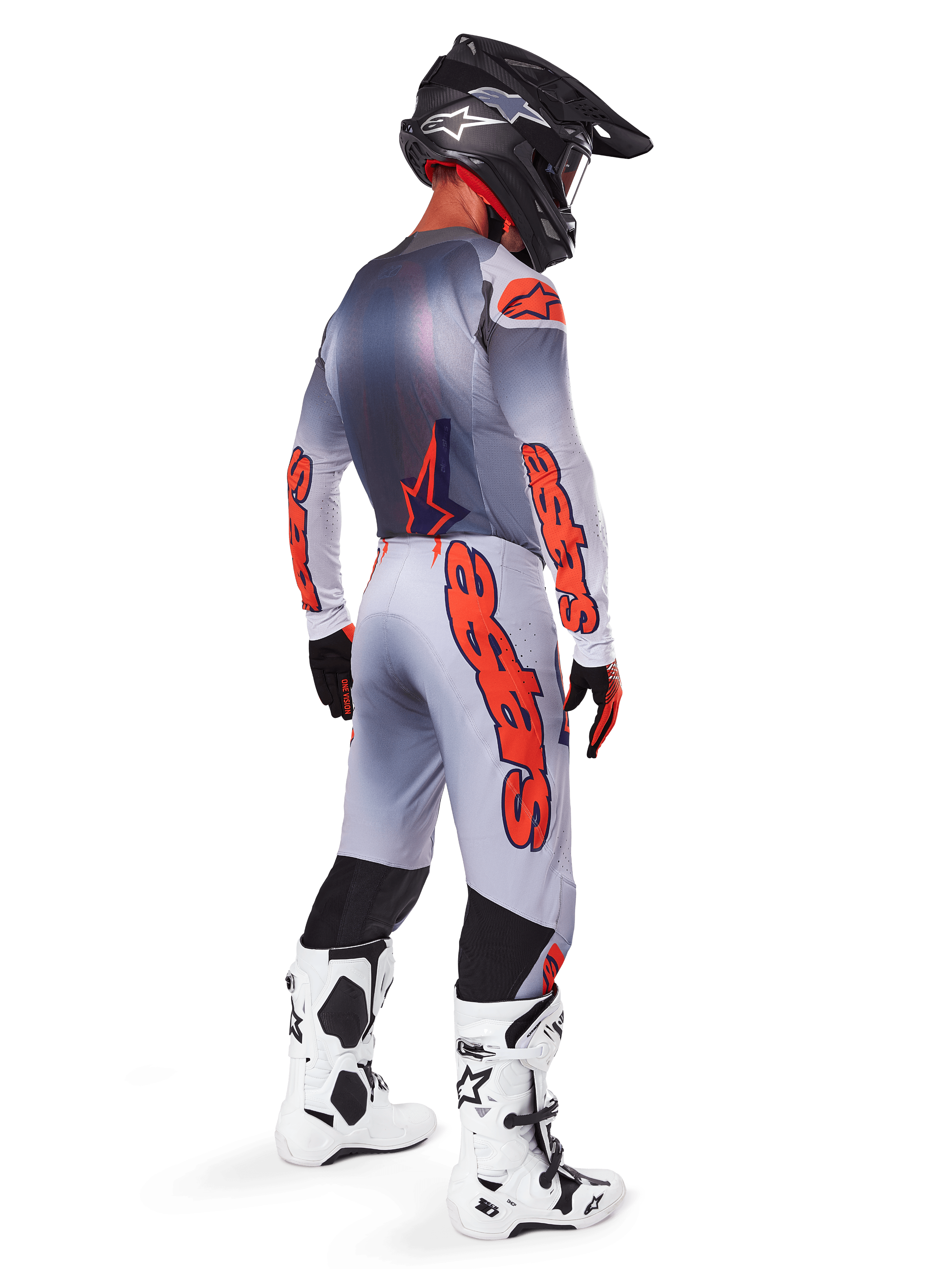 Motocross-Fahrer von hinten im 2025 Supertech Lipan Gear Set, Trikot in Grau und Orange Fluo mit passender Hose, markantes orangefarbenes Alpinestars-Branding auf Ärmeln und Beinen, schwarzer Helm, weiß-schwarze Motocross-Stiefel, professionelles Offroad-Rennoutfit.