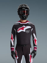 Alpinestars 2026 Supertech AFD Vista Trikot, Motocross-Trikot in Schwarz, Rot und Weiß, abgebildet an einem Fahrer mit schwarzem Helm, Goggle und Handschuhen, mit großem Brustlogo und 'SUPERTECH AFD'-Branding, professionelle Rennausrüstung für Offroad-Performance