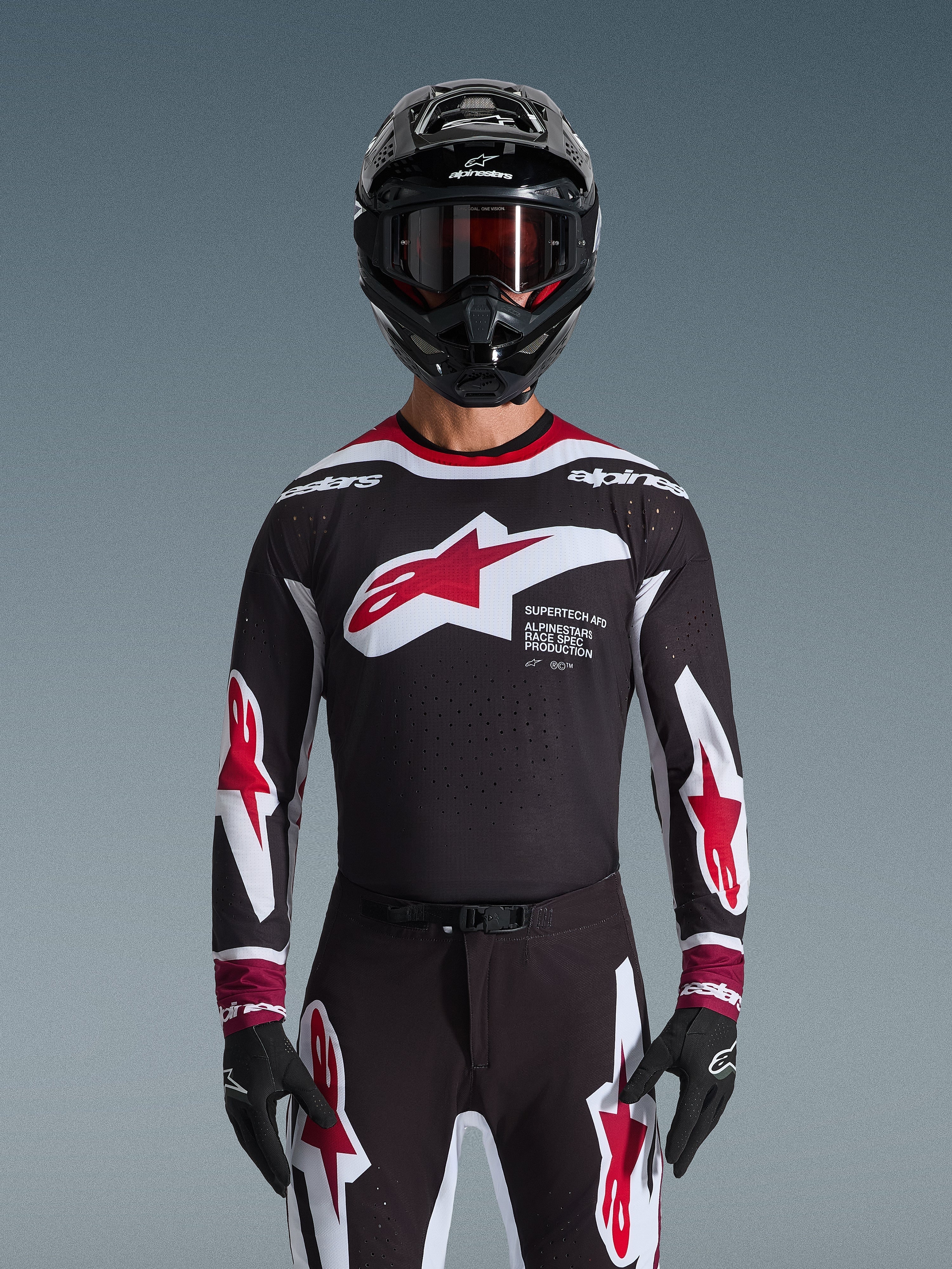 Alpinestars 2026 Supertech AFD Vista Jersey, Motocross Jersey in Black Red and White, shown on a rider with a black helmet, goggles, and gloves, featuring a large chest logo and 'SUPERTECH AFD' branding, professional racing gear for off-road performance