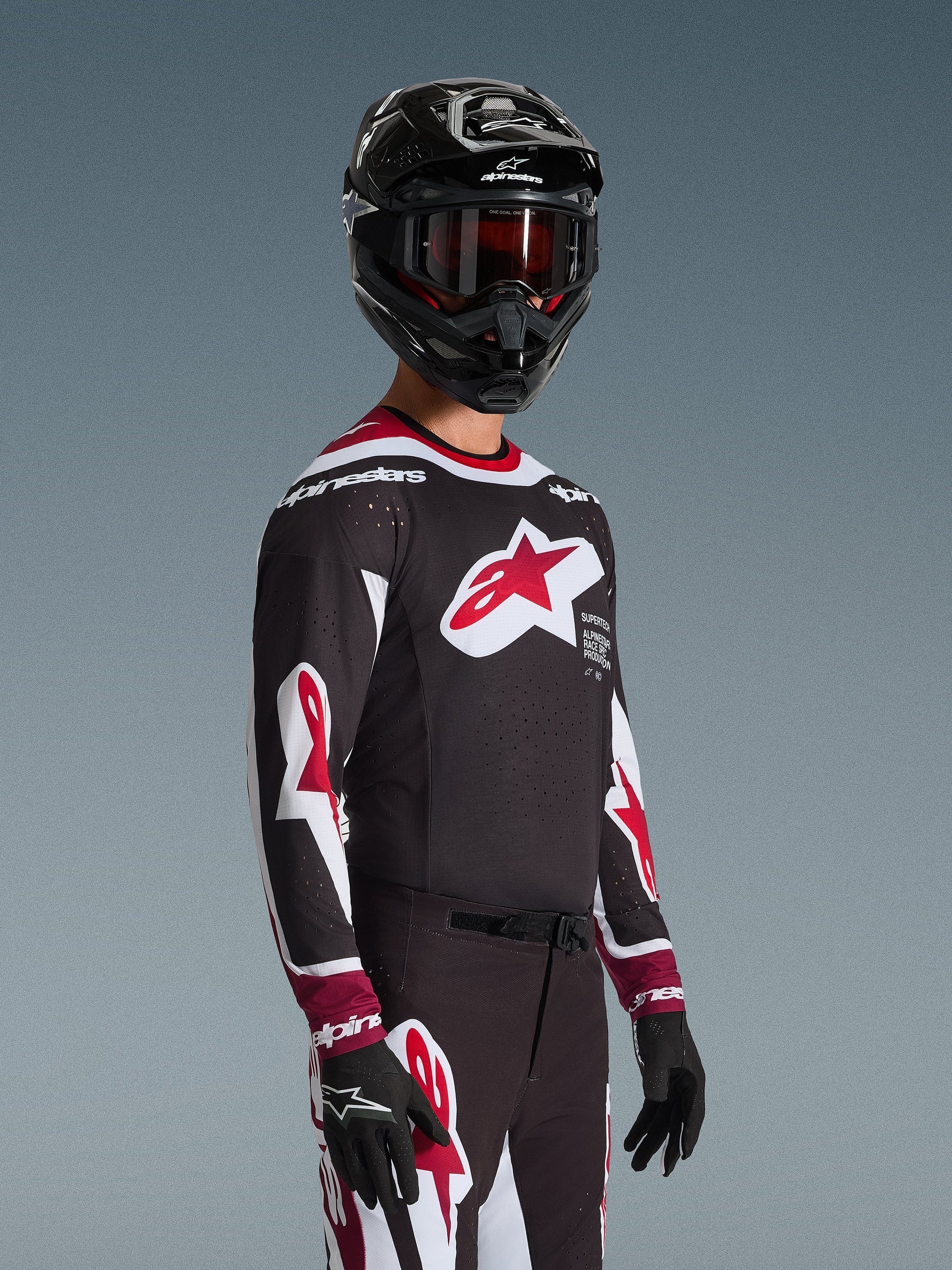 Motocross-Fahrer im Alpinestars 2026 Supertech AFD Vista Trikot in Schwarz, Rot und Weiß, mit einem großen roten Stern-Logo auf der Brust und lasergeschnittenen Perforationen, kombiniert mit einem schwarzen Helm und passender Rennhose für Offroad-Performance
