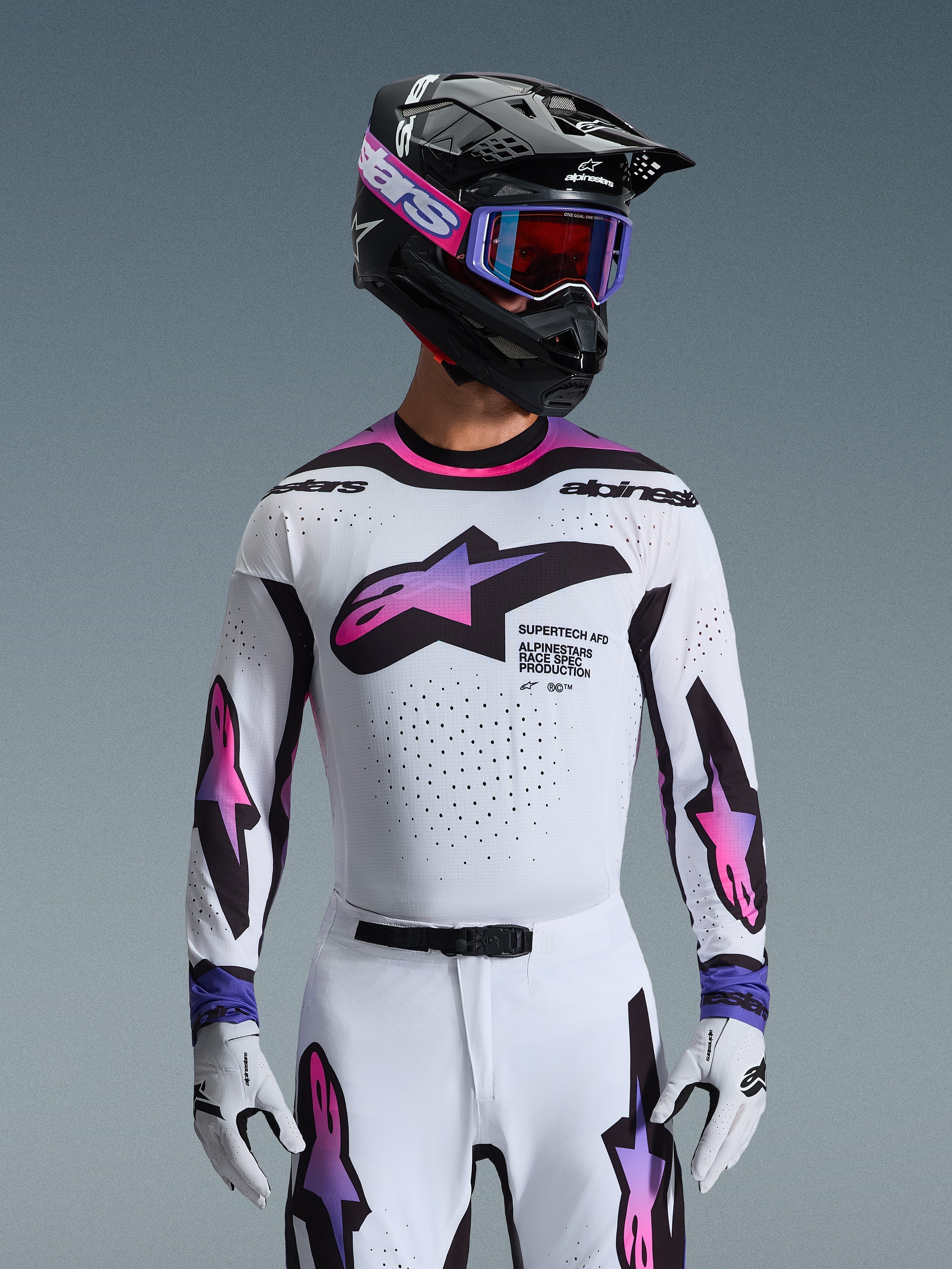 Motocross-Fahrer im 2026 Supertech AFD Vista Trikot in Weiß, Lila und Schwarz, mit schwarzem Helm mit pinkfarbenem Branding, lila Goggle und passenden weißen Handschuhen, athletische Passform für professionelle Offroad-Rennperformance