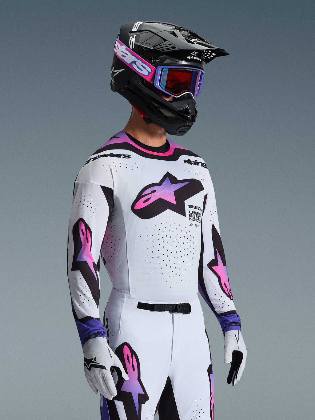 Motocross-Fahrer trägt das 2026 Supertech AFD Vista Trikot in Weiß Violett Schwarz, passende weiß-violette Hose, schwarzer Helm mit violetter Brille und weiße Handschuhe, komplette professionelle Offroad-Rennausrüstung.