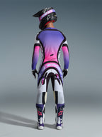 Motocross-Fahrer in der Rückansicht mit dem 2026 Supertech AFD Vista Trikot, Weiß, Lila und Schwarz mit pinkfarbenen Farbverlauf-Akzenten, passende Motocross-Hose, schwarzer Helm mit pinker Brille und weiß-lila Stiefel, komplettes professionelles Rennausrüstungs-Set