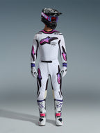 Motocross-Fahrer in kompletter Rennausrüstung, Alpinestars 2026 Supertech AFD Vista Trikot in Weiß Lila Schwarz, passende weiße Hose mit lila-rosa Farbverlauf-Grafiken, weiße Stiefel, schwarzer Helm mit lila Brille, professionelles Offroad-Rennoutfit