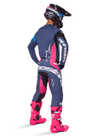 Motocross-Fahrer in der Rückansicht, trägt das Alpinestars 2025 Techstar Dreem Gear Set, Grau mit leuchtend pinken und weißen Akzenten, schwarz-weißer Helm und leuchtend pinke Stiefel, komplette Rennausrüstung für Motocross-Performance.