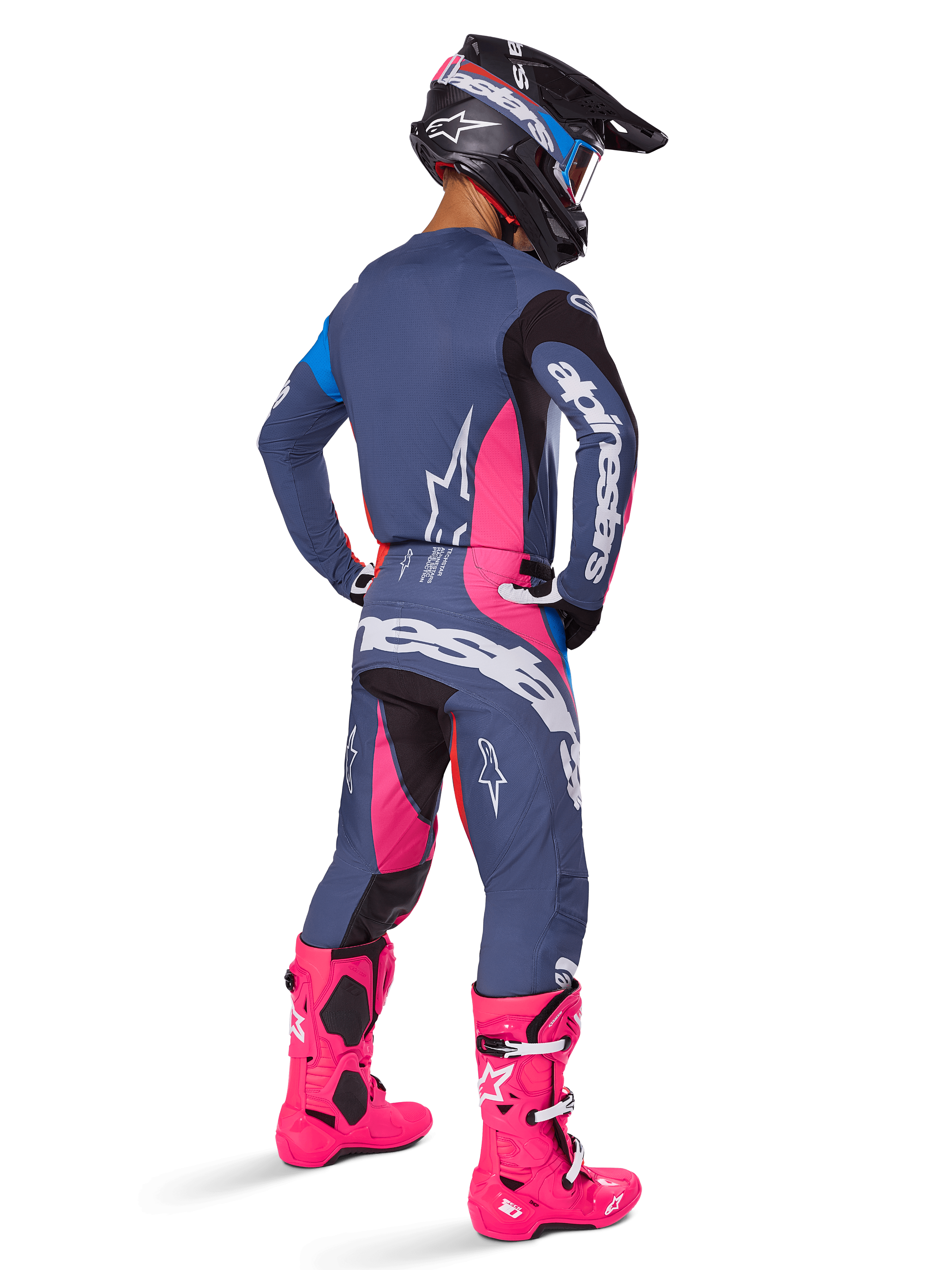 Motocross-Fahrer in der Rückansicht, trägt das Alpinestars 2025 Techstar Dreem Gear Set, Grau mit leuchtend pinken und weißen Akzenten, schwarz-weißer Helm und leuchtend pinke Stiefel, komplette Rennausrüstung für Motocross-Performance.