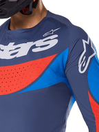 Nahaufnahme des Alpinestars 2025 Techstar Dreem Trikots, Marineblau mit leuchtend blauen und orangefarbenen Akzenten, weißes Alpinestars-Branding auf Brust und Schulter, mit lasergeschnittenen Perforationen zur Belüftung