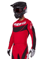 Alpinestars 2025 Techstar Dreem Gear Set, Red Motocross Jersey and Pants with black and white accents, worn with a black helmet and goggles, white and black gloves, featuring bold 'astars' branding, designed for performance off-road racing