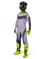 Alpinestars 2025 Techstar Dreem Gear Set, Motocross rider in full racing outfit, gray jersey and pants with dark gray patterns and neon yellow-green accents, matching black helmet, neon yellow-green gloves and boots, performance off-road gear