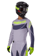 Motocross rider wearing Alpinestars 2025 Techstar Dreem Jersey, Gray and Dark Gray with lime green logos, matching pants, black helmet with lime green accents, lime green and black gloves, coordinated outfit for off-road racing