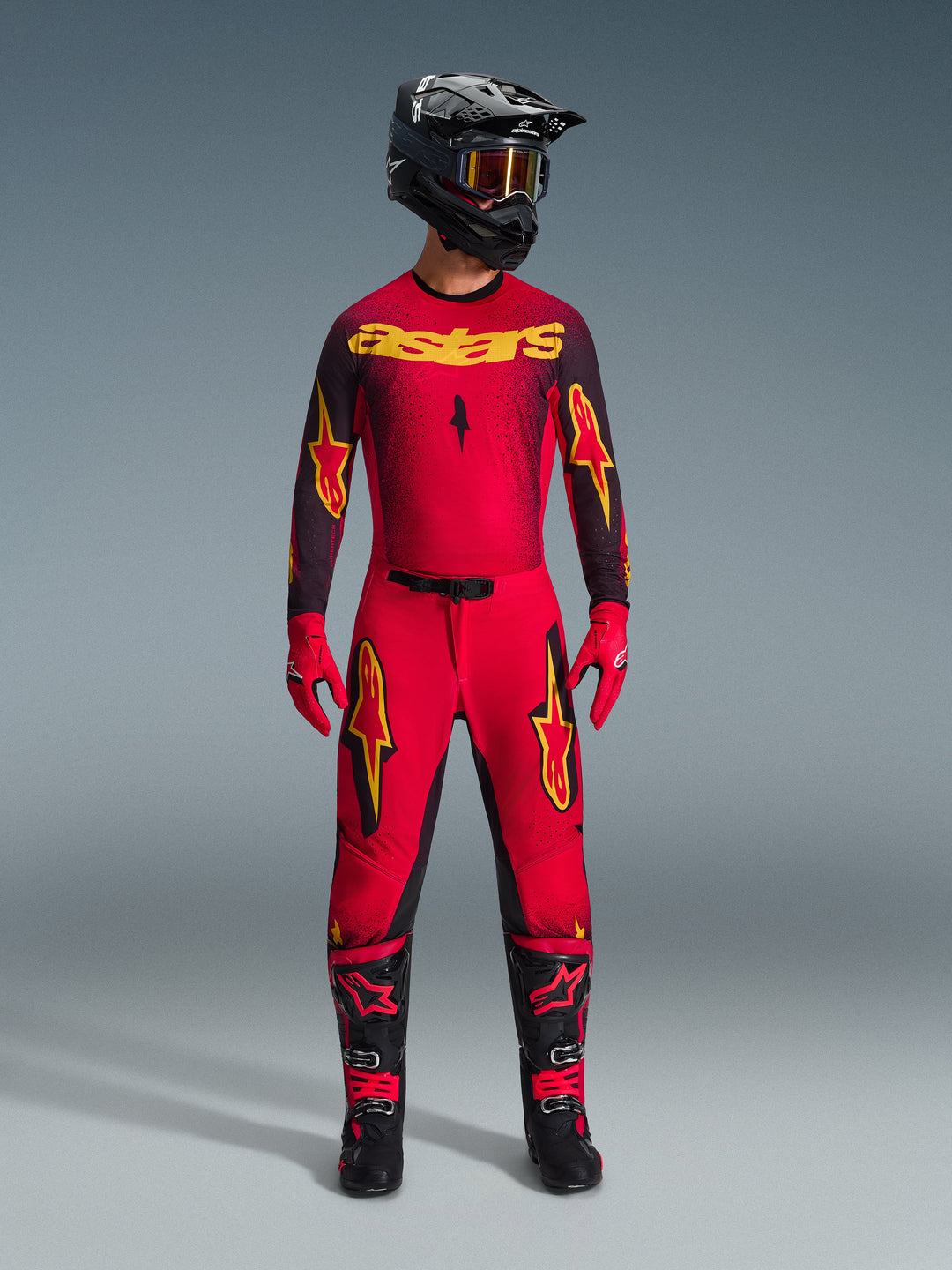Alpinestars 2026 Supertech Scenz Gear Set, komplette Motocross-Rennausrüstung in Rot und Schwarz mit gelben Grafiken, bestehend aus Profi-Jersey und passender Hose, getragen mit schwarzem Helm, roten Handschuhen und schwarzen Rennstiefeln, hochwertige Performance-Ausrüstung für den Offroad-Wettbewerb