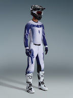 Alpinestars 2026 Supertech Scenz Gear Set, Motocross rider wearing white and navy blue racing jersey and pants with a gradient stipple effect, features bold Astars branding, paired with a black and white helmet, navy gloves, and white motocross boots.