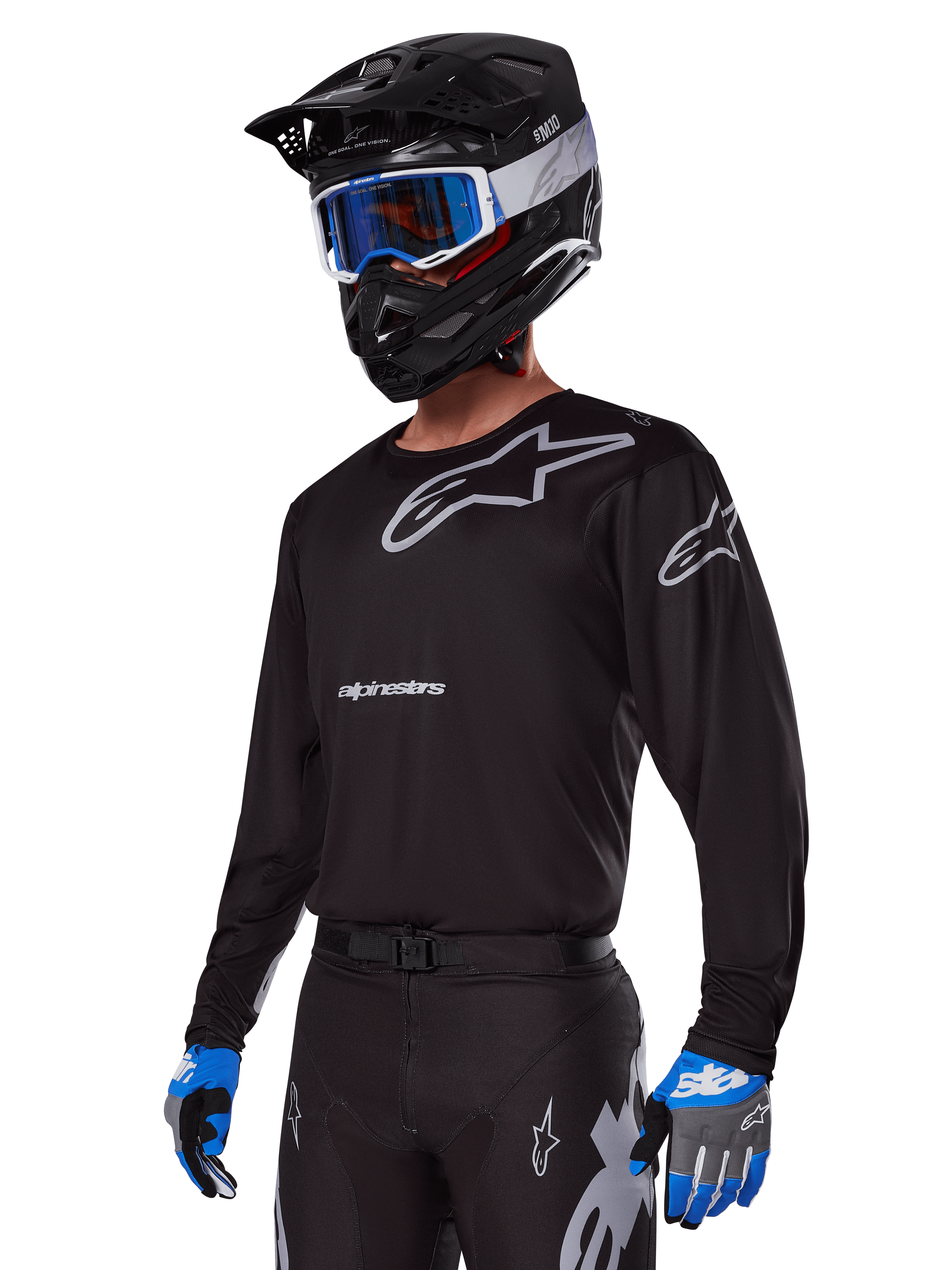Motocross-Fahrer im Alpinestars 2025 Racer Graphite Ausrüstungsset, schwarzes Jersey mit grauen Alpinestars-Logos, passende schwarze Hose mit grauen Akzenten, schwarzer Helm mit blau-weißer Brille, blau-graue Handschuhe, elegantes technisches Outfit für Offroad-Rennsport